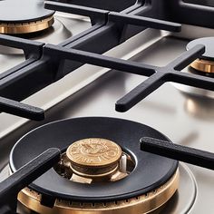 a gold coin is sitting on the burners of a gas stove top that's stainless steel