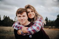 a man and woman hugging each other in the middle of a field