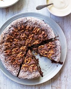 a chocolate cake with walnuts and powdered sugar on top, cut into slices