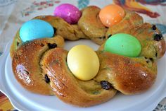 a white plate topped with buns covered in chocolate and colored eggs on top of it