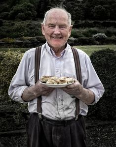 an older man holding a plate with food on it