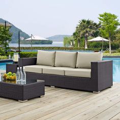 a couch and table sitting on top of a wooden deck next to a swimming pool