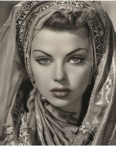 a woman wearing a veil and headdress is posing for the camera with her eyes closed