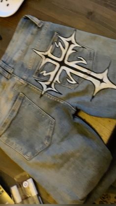 an old pair of jeans with a cross painted on the side and other items around it