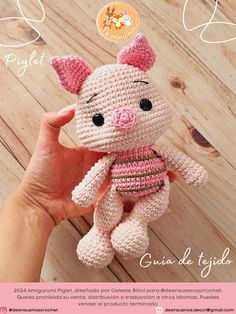 a crocheted pig stuffed animal in pink and white is held up by someone's hand