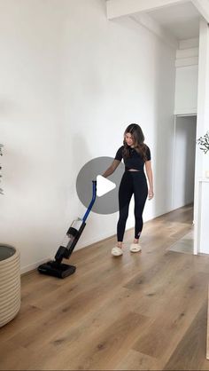 a woman is cleaning the floor with a vacuum