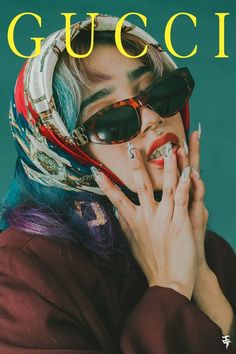 a woman with colorful hair and sunglasses covers her face as she holds her hands to her mouth