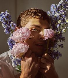 a man holding flowers in front of his face