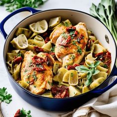 a pan filled with pasta and chicken covered in sauce, garnished with parsley