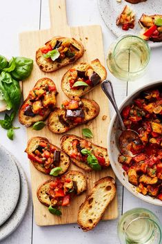 some breads are sitting on a cutting board next to glasses and plates with food