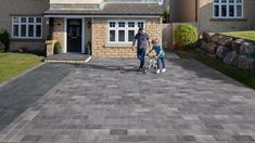 a man and two children are standing in front of a house with a large driveway