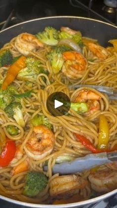 a pan filled with shrimp, broccoli and noodles