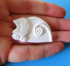 a hand holding a small white ceramic animal