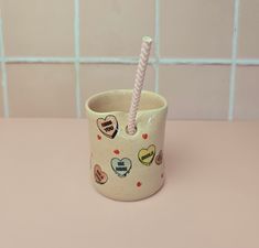 a cup with a straw sticking out of it on a pink table next to a tiled wall