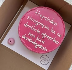 a pink cake in a cardboard box with german words on the top and bottom side