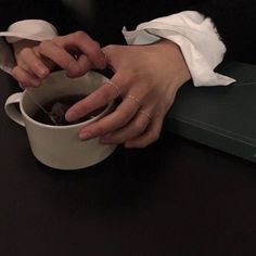 a woman holding a cup of coffee with her hands on top of the cup and napkins in front of her