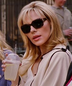 a woman wearing sunglasses and holding a drink