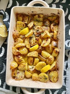 a casserole dish with potatoes and lemons on a blue and white tablecloth