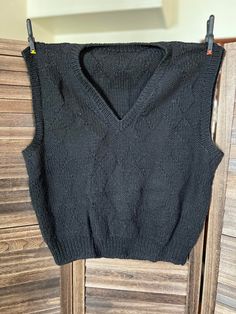 This gorgeous hand knit black wool sweater vest was lovingly created by Georgene Johnson of Hays Kansas. It uses multiple stitches throughout the design. The Unisex sweater vest measures 44 inches wide by 25 inches long.  Care: Dry clean or hand wash cold/gentle cycle. Condition: Very Good Fitted Black Sweater Vest, Winter Knit Black Vest, Black Knit Winter Vest, Black Knit Vest For Winter, Winter Black Knit Vest, Black Fitted Sleeveless Sweater, Fitted Black Sleeveless Sweater, Fitted Sleeveless Black Sweater, Black Knitted Sleeveless Sweater Vest