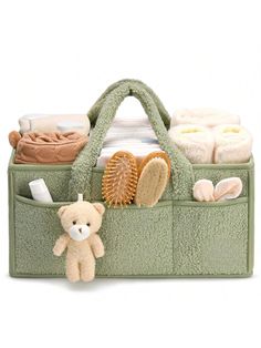 a teddy bear sitting inside of a green bag filled with towels and other items on top of it