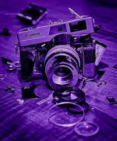 an old camera sitting on top of a wooden table next to other broken up objects