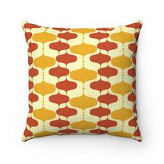 a yellow and red pillow with an abstract design on the front, sitting against a white background