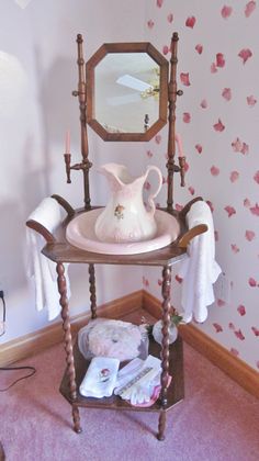 a table with a mirror, vase and other items on it in front of a wallpapered background