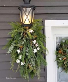 two wreaths hanging from the side of a house next to a door with a light on it