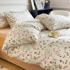 a bed with white and pink flowers on it in a room next to a table