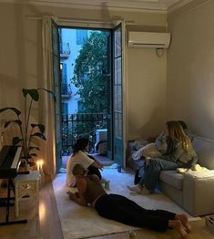 two women sitting on the floor in front of a living room door, with one woman laying on the floor