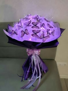 a bouquet of purple flowers with lights in the shape of butterflies on it sitting on a couch