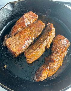 three pieces of meat cooking in a skillet