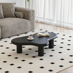 a black coffee table sitting on top of a white rug in front of a couch