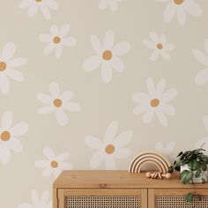 a wooden cabinet sitting next to a wall with flowers painted on the wall behind it