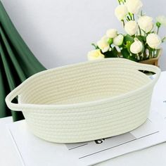 a white bowl sitting on top of a table next to flowers and a planter