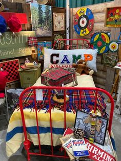 a red metal bed frame with various items on it in a room filled with vintage memorabilia