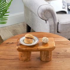 a wooden table topped with two cookies on top of a white plate next to a gray couch