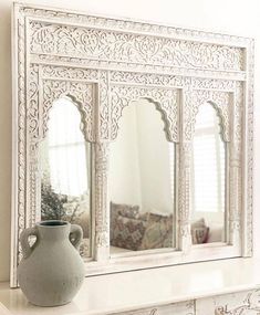 a white mirror sitting on top of a mantle