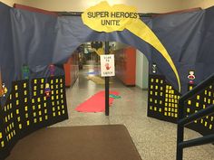 an entrance to a school with paper cutouts on the floor and a sign that says super hero unit