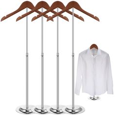 three wooden clothes hangers and two metal pants on stands with one white shirt hanging from the