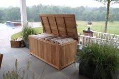 a wooden chest sitting on top of a patio next to a potted planter