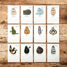 six calendars with cats drawn on them sitting on a table next to each other