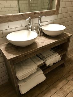 two white bowls are sitting on a wooden counter in front of a mirror and sink