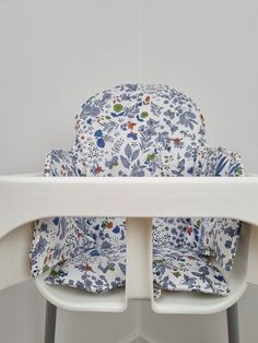 a high chair with a blue and white floral seat cover on it's back