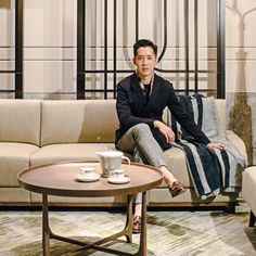 a man sitting on top of a couch next to a table with a coffee cup