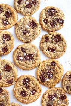 chocolate chip cookies are arranged on a white paper lined baking sheet, ready to be eaten