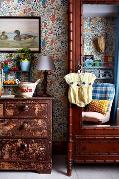 an old dresser is next to a wallpapered room with birds and flowers on it