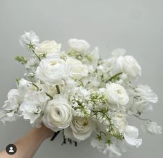 a bouquet of white flowers in someone's hand