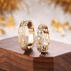 two gold wedding rings sitting on top of a wooden table next to another ring with diamonds