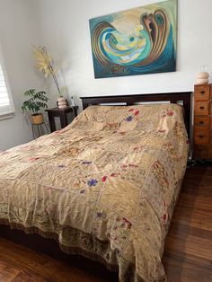 a bed sitting in a bedroom next to a painting on the wall and wooden floors